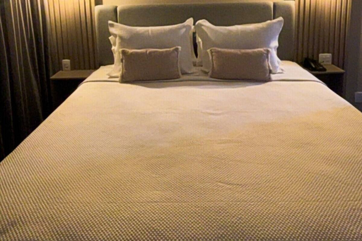 Ein Hotelzimmer mit einem großen Bett, zwei Nachttischen und Vorhängen.