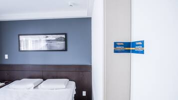 Quarto de hotel com uma cama, um quadro na parede e uma placa indicando o tipo de quarto.