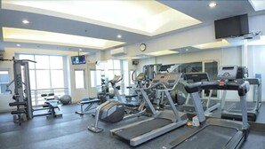 Een fitnessruimte met loopbanden, krachttrainingapparatuur en fitnessballen.