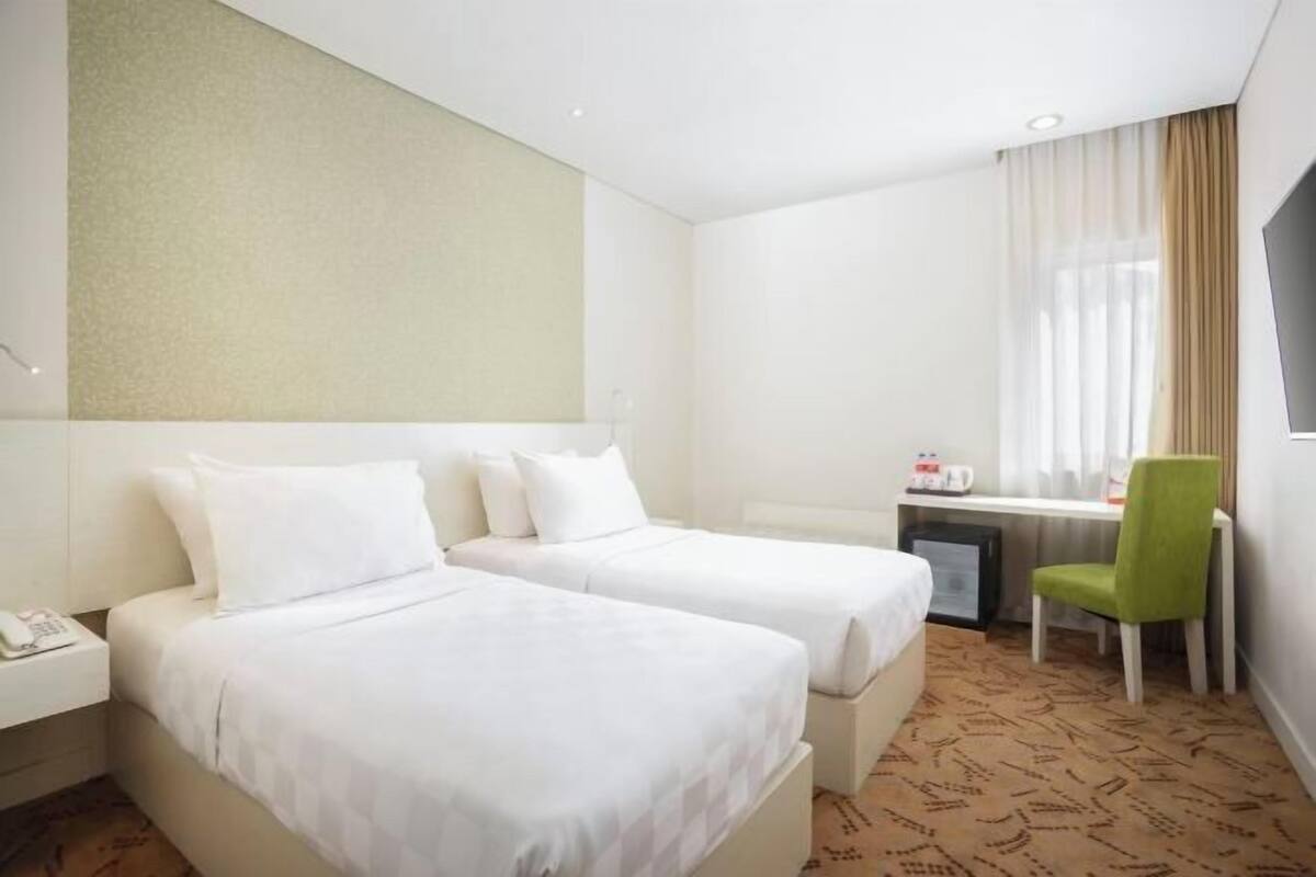 Een hotelkamer met twee bedden, een bureau, een stoel en een televisie.