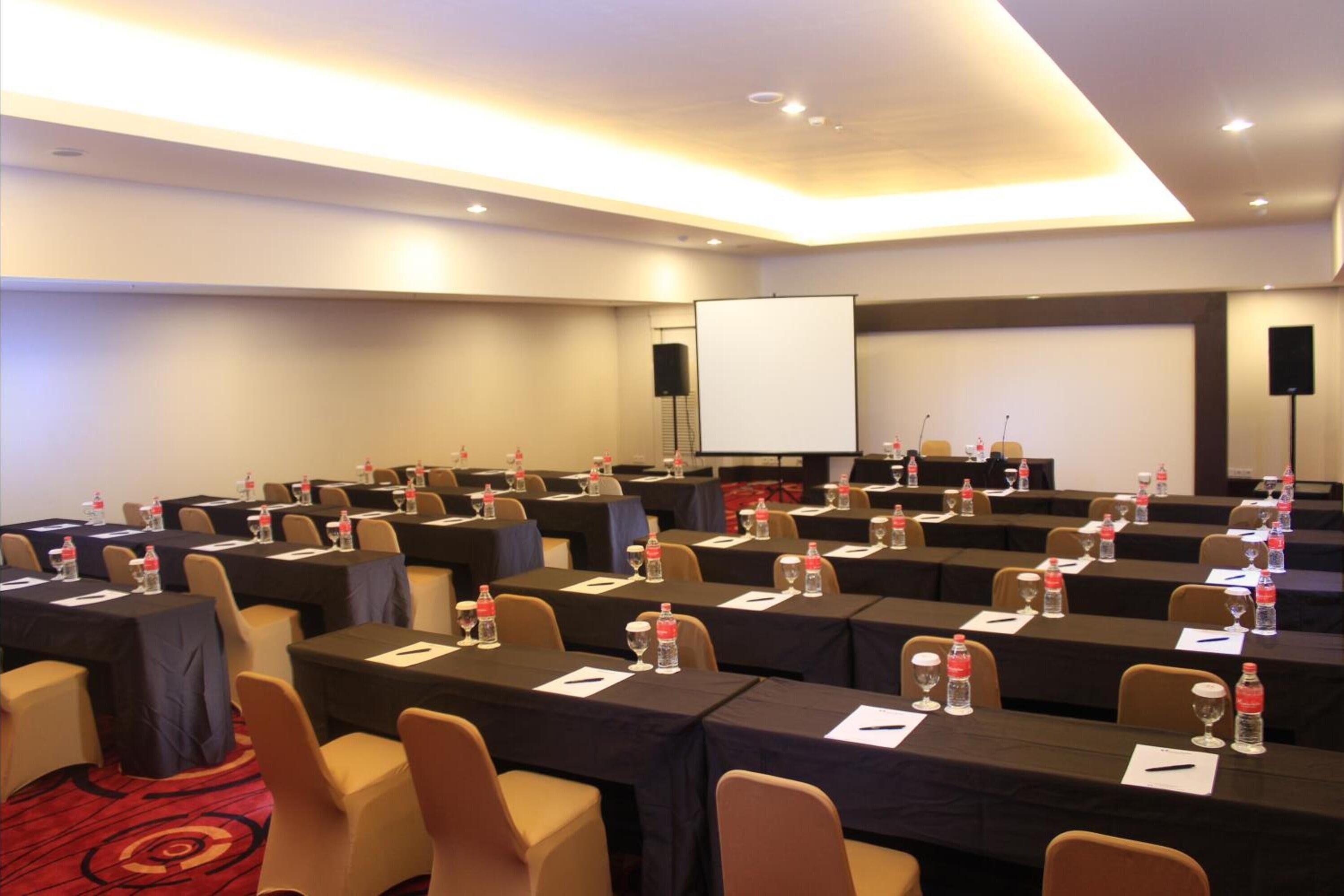 A conference room with rows of tables, each with water bottles and name cards.