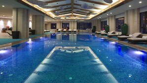 A large indoor swimming pool with lounge chairs and a modern ceiling design. - Sheraton Changbaishan Resort (Baishan)