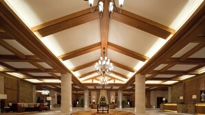 A spacious lobby with high ceilings, wooden beams, a chandelier, a reception desk, and a central floral arrangement. - Sheraton Changbaishan Resort (Baishan)