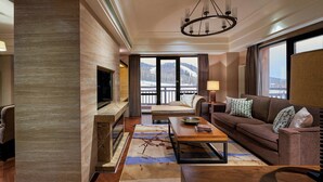 A modern living room with a fireplace, comfortable seating, and a large window offering a view of a snowy landscape. - Sheraton Changbaishan Resort (Baishan)