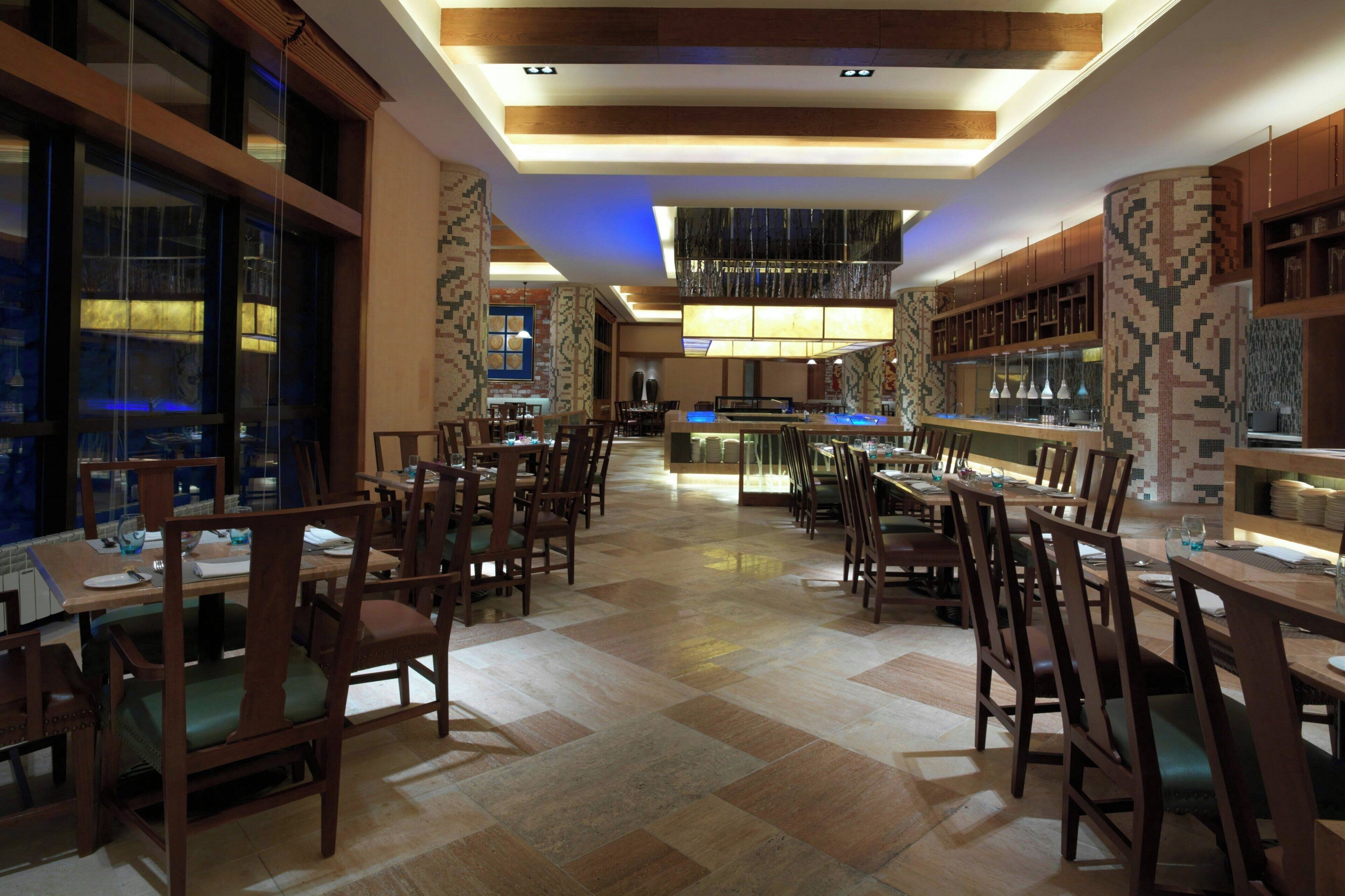 Ein Restaurant mit mehreren Tischen und Stühlen, einer Bar und einer Wand mit Musterdesign.