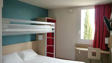 A room with a bunk bed, a desk with a chair, a red wardrobe, and a window with curtains.