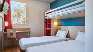 A hotel room with two beds, a desk, a chair, a TV, and a window with a view of trees.