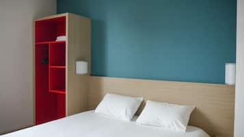 Una habitación de hotel con una cama, un armario rojo y dos lámparas fijadas a la pared.