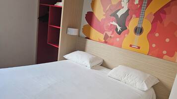 A hotel room with a bed, a red wardrobe, and a wall mural featuring a guitar and the word "Flamenco".