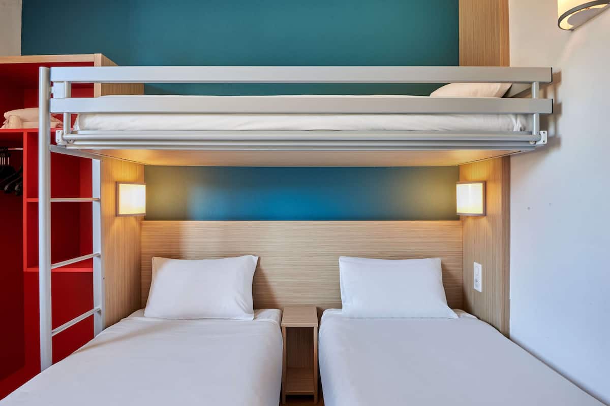 Een slaapkamer met een stapelbed, een rode garderobe en een blauwe muur.