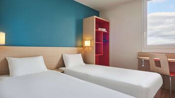A hotel room with two beds, a desk, and a wardrobe.