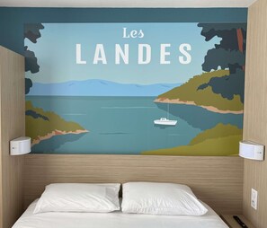 Ein Schlafzimmer mit einer Wandmalerei namens „Les LANDS“, die eine Küstenlandschaft mit einem Boot zeigt.