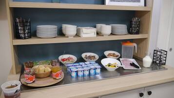 A breakfast buffet setup with various food items and utensils.