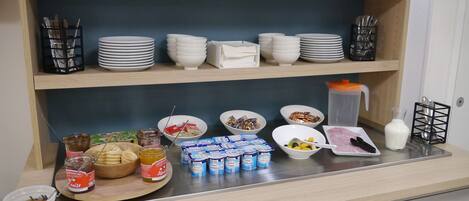 A breakfast buffet setup with various food items and utensils.