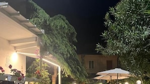 Un patio al aire libre con suelo de piedra, plantas en macetas y mobiliario exterior.