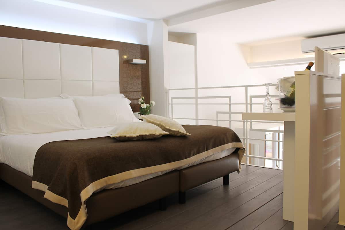 A bedroom with a large bed, a bedside table, and a view of the outside.