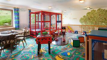 Kids can play on a colorful play mat with a road and vehicle theme, featuring a play structure and stools.