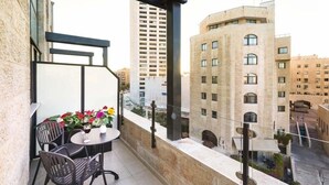 A balcony with a table and chairs, overlooking a cityscape with buildings. - City Center Jerusalem (Jerusalem)