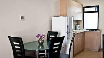 A compact kitchen with a refrigerator, a sink, and a window.
