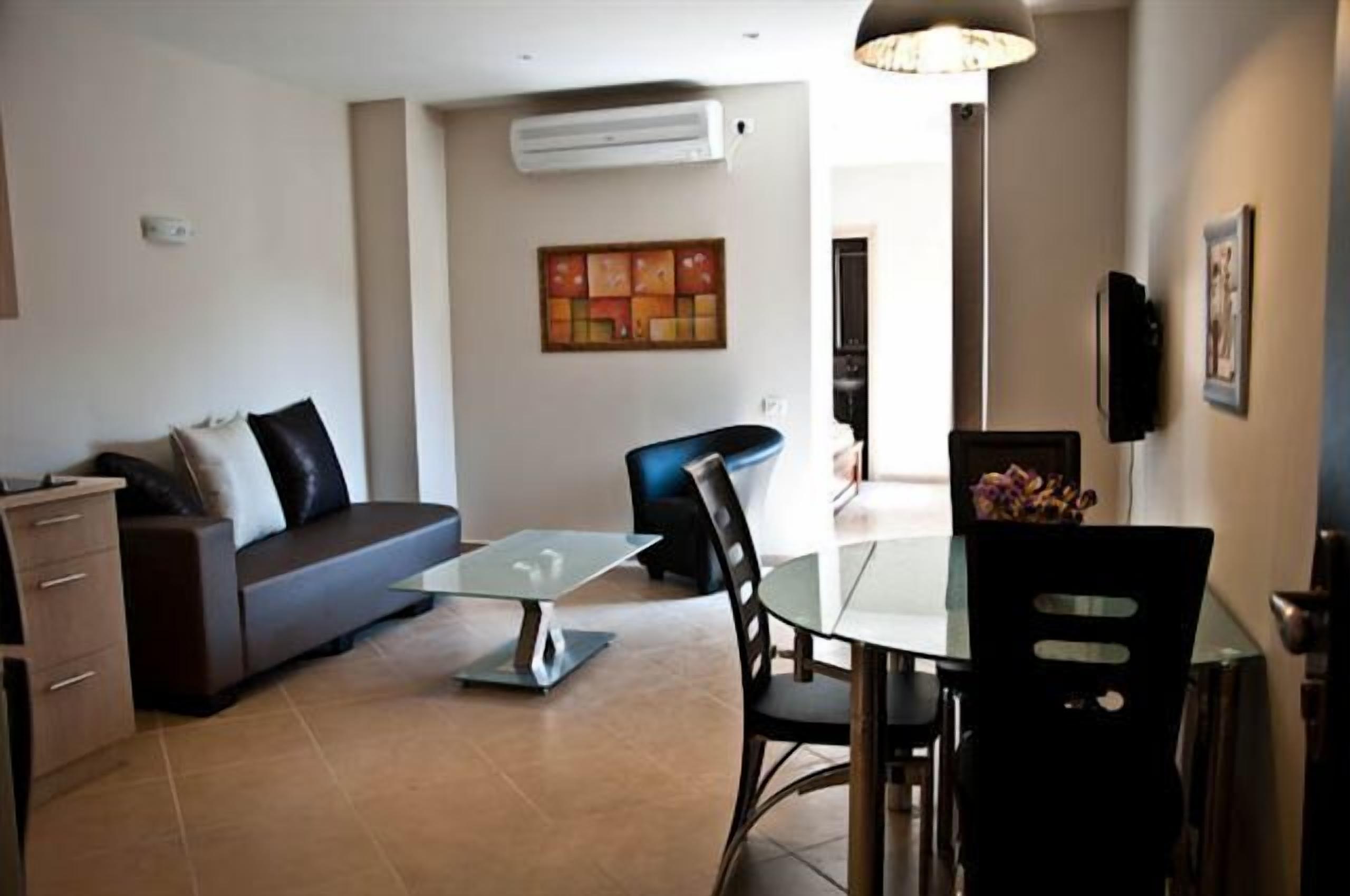 Una sala de estar moderna con un sofá, una mesa de centro de vidrio y un comedor con mesa y sillas.