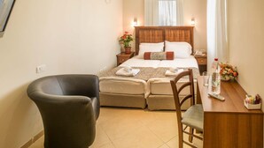 A hotel room with a bed, a chair, a desk with a bottle and glasses, and a potted plant. - City Center Jerusalem (Jerusalem)