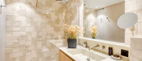 A modern bathroom with a large sink, a mirror, and a shower area.
