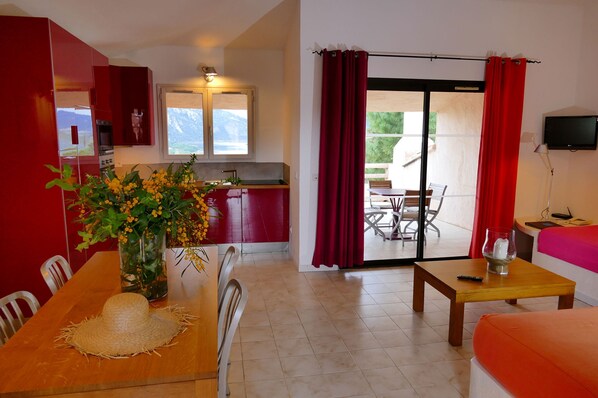 Una habitación con una mesa de comedor, sillas, una zona de cocina, un sofá y un televisor.