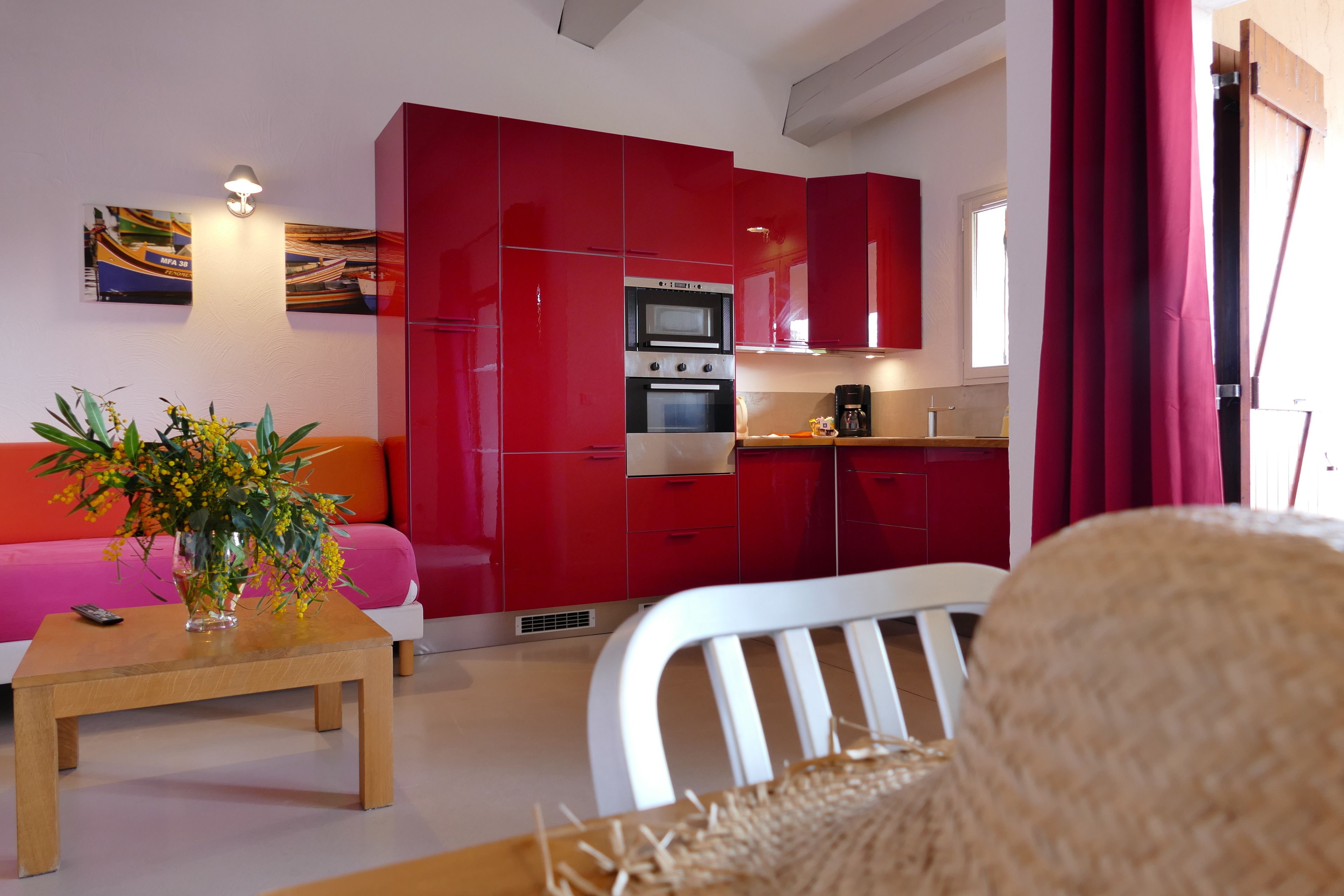 Una cocina moderna con armarios rojos, horno integrado y cafetera.