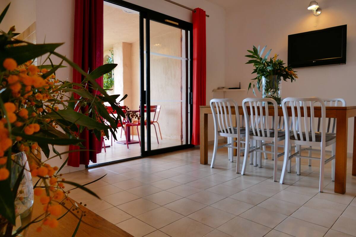 Un coin repas avec une table et des chaises, une porte-fenêtre coulissante et une plante en pot.