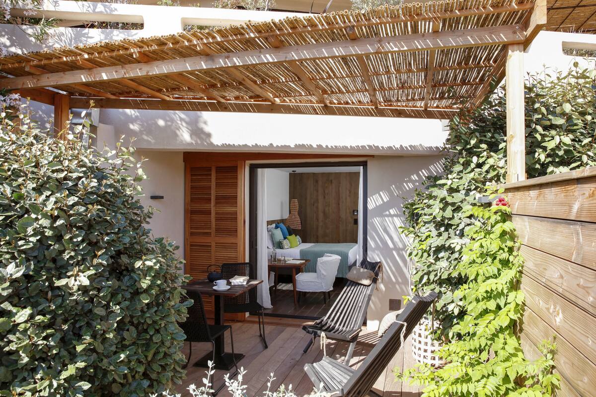 Une agréable terrasse extérieure agrémentée d’une pergola en bois, d’un coin salon avec un hamac et d’une petite table avec une chaise.