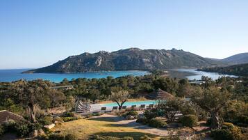 A coastal landscape with a mountain, a body of water, and a building with a blue roof.