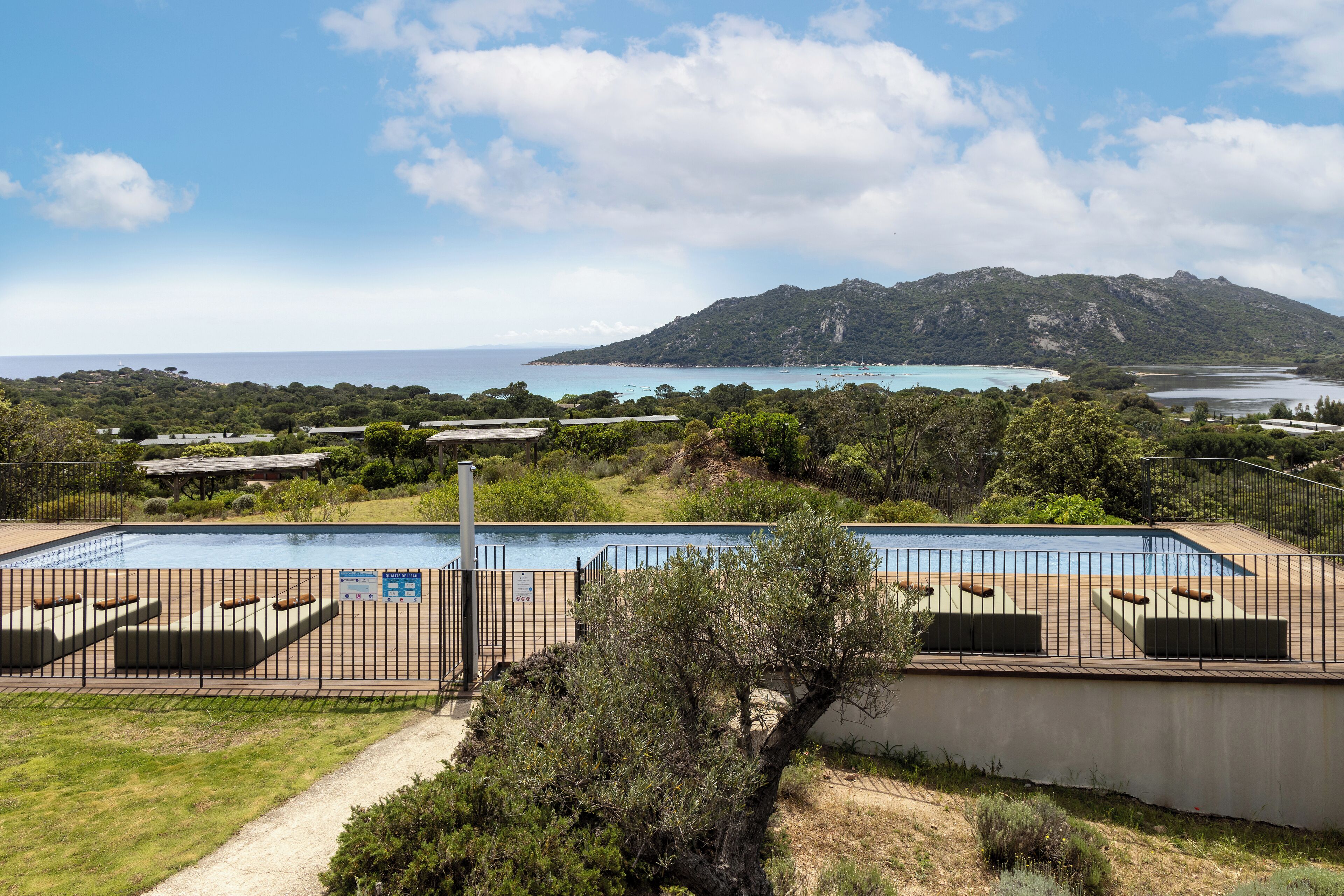 A pool area with a view of the sea and a mountain in the background.