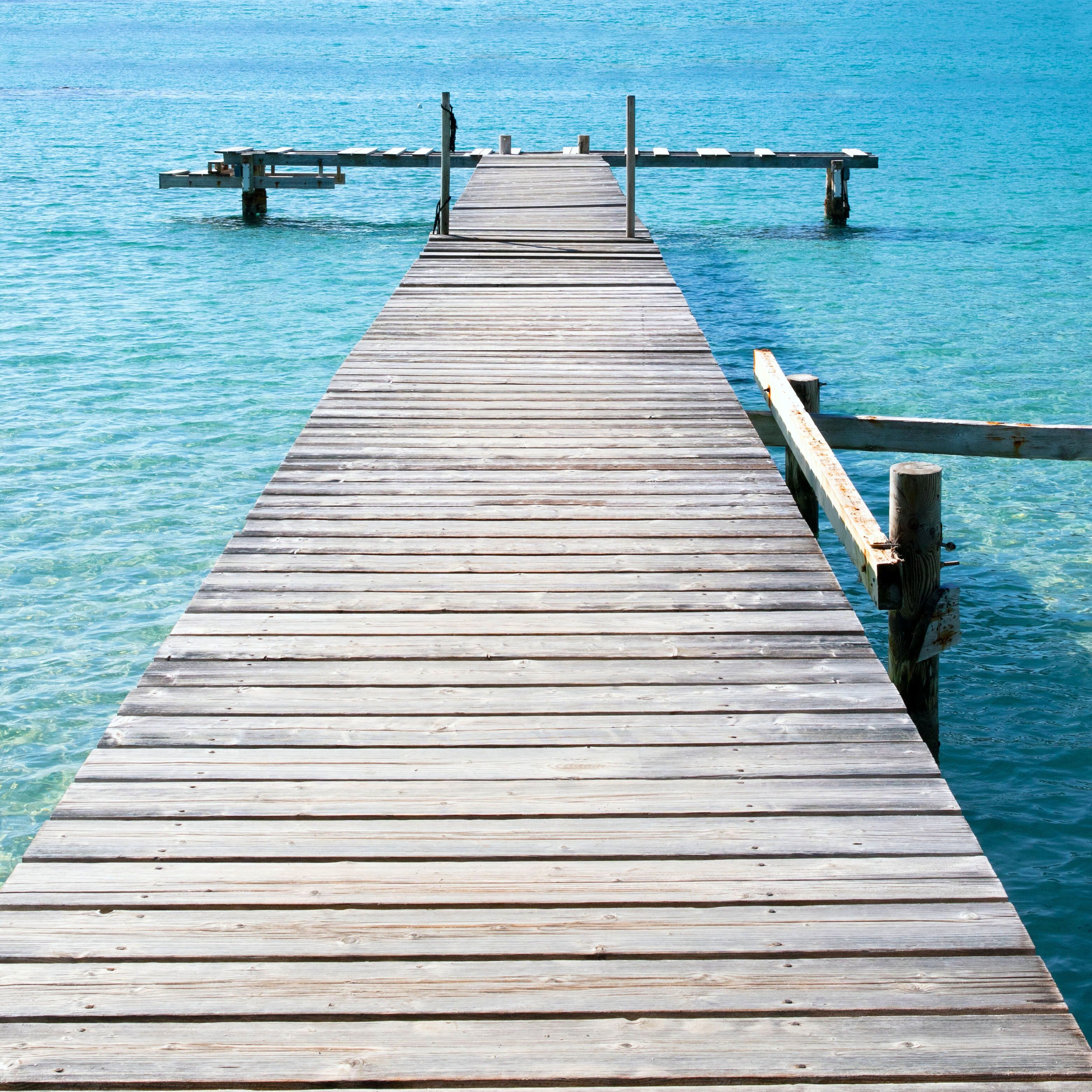 Un muelle de madera que se adentra en un cuerpo de agua azul cristalino.