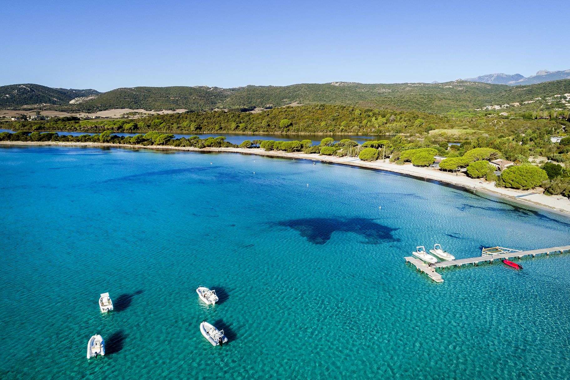 A coastal area with clear blue waters, boats, and a dock.