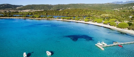 Uma área costeira com águas azul-claras, barcos e um cais.