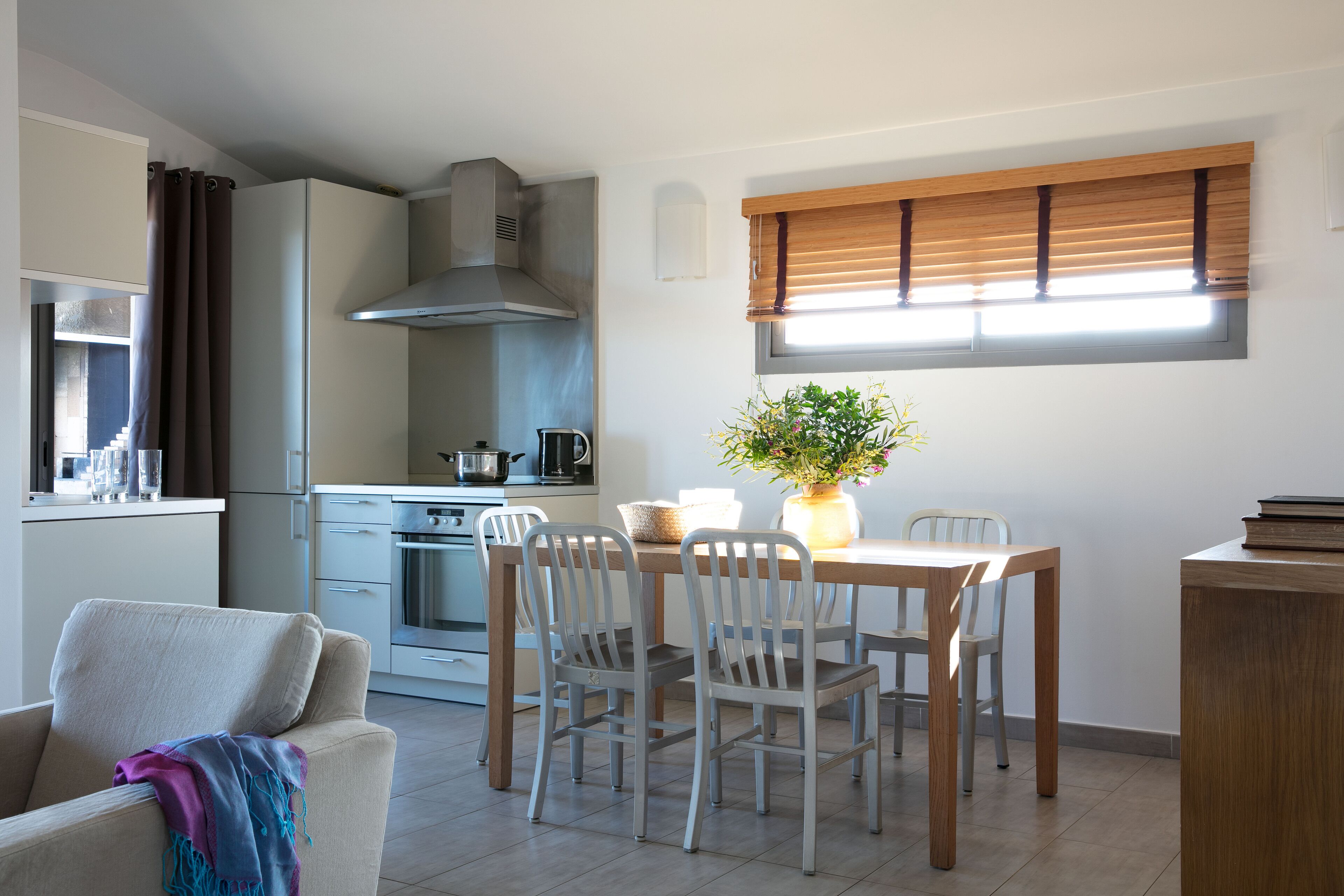 Una cocina compacta con comedor, un sofá y una ventana con persianas.