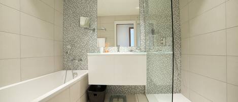 A modern bathroom with a large bathtub, a glass shower enclosure, and a white vanity.