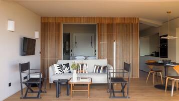 A modern living room with a sofa, coffee table, and chairs. There is a kitchen area in the background.