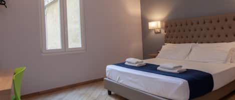 Un dormitorio con cama, ventana, silla y escritorio.