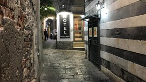 Une étroite ruelle pavée mène à l’entrée d’un hôtel, où un panneau indique « HÔTEL GENZIANA ».