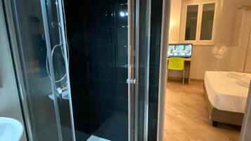 Une salle de bain moderne avec une douche à l’italienne en verre, un lavabo blanc et un plancher en bois.