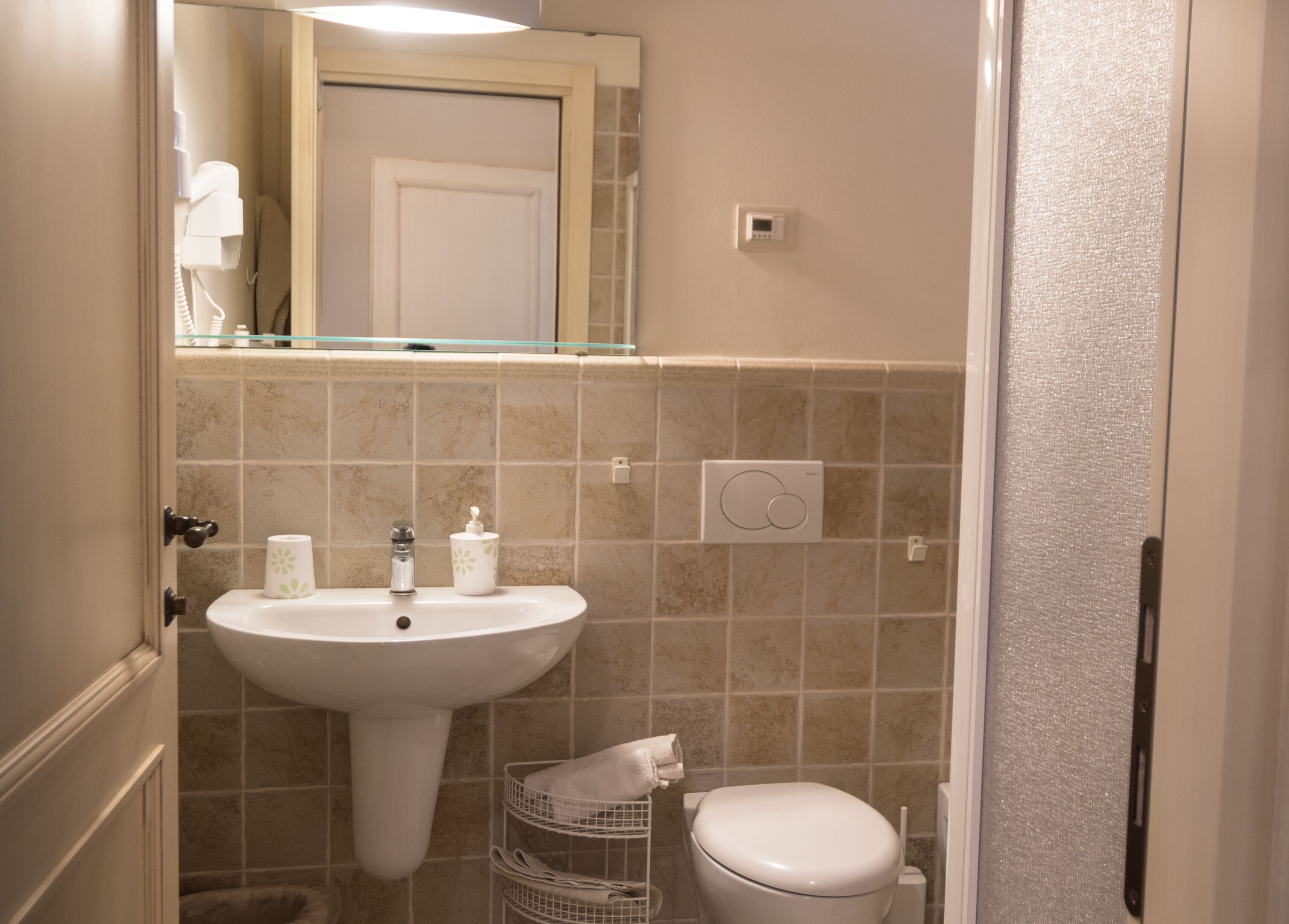 Ein Badezimmer mit einem Standwaschbecken, einer Toilette und einem Spiegel über dem Waschbecken.