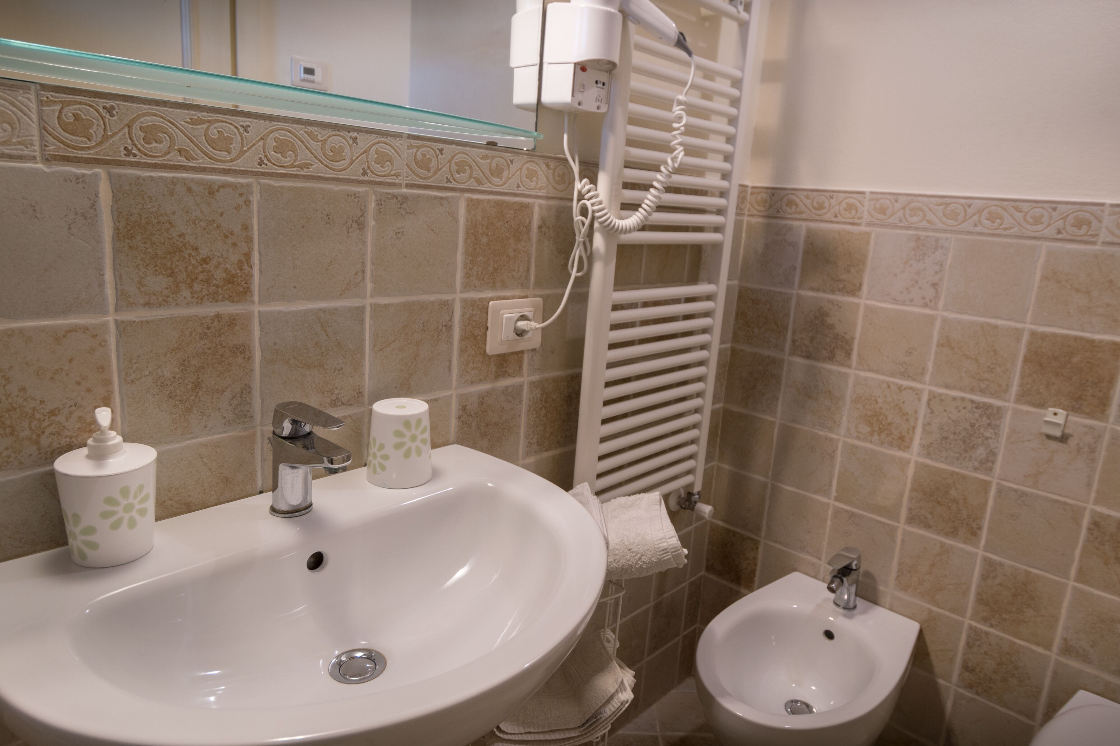 Un baño con un lavamanos grande, un bidé y un perchero para toallas.