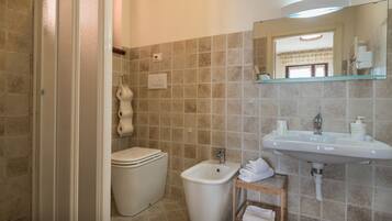 A bathroom with a toilet, bidet, sink, and a mirror above the sink.