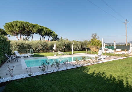 Una piscina al aire libre de temporada, sombrillas
