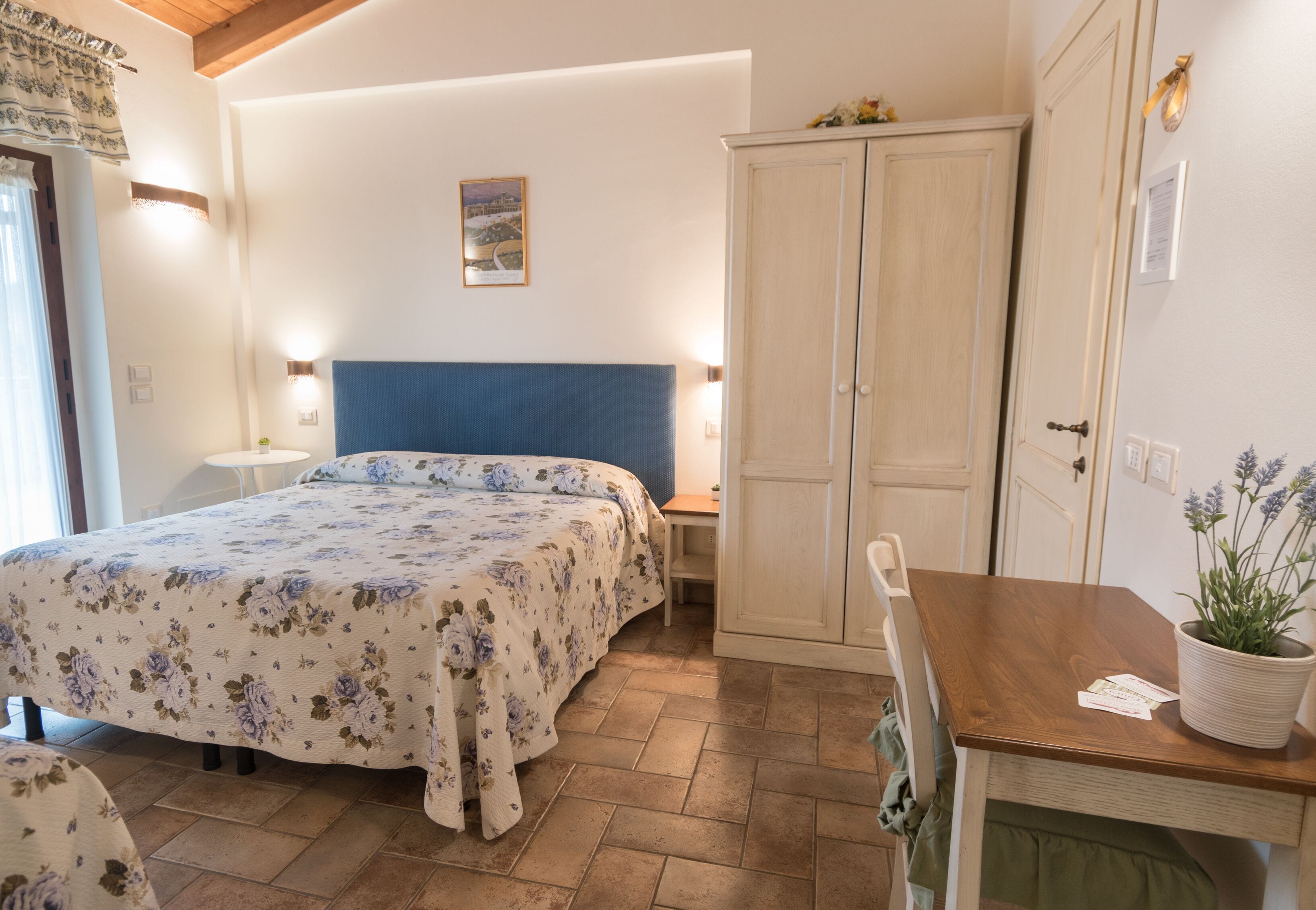 A bedroom with a bed, bedside tables, a wardrobe, and a small table with a plant.