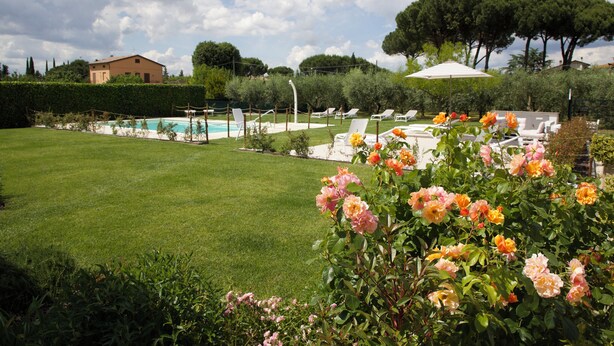 A pool area with lounge chairs and a house in the background. - Rosa di Assisi (Bastia Umbra)