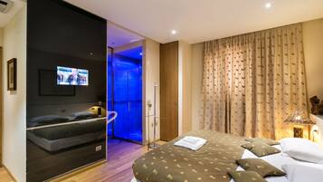 A modern hotel room with a large bed, a television, and a glass-enclosed shower area.