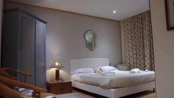Une chambre à coucher avec un lit, une table de chevet, une lampe, une armoire et un miroir au mur.