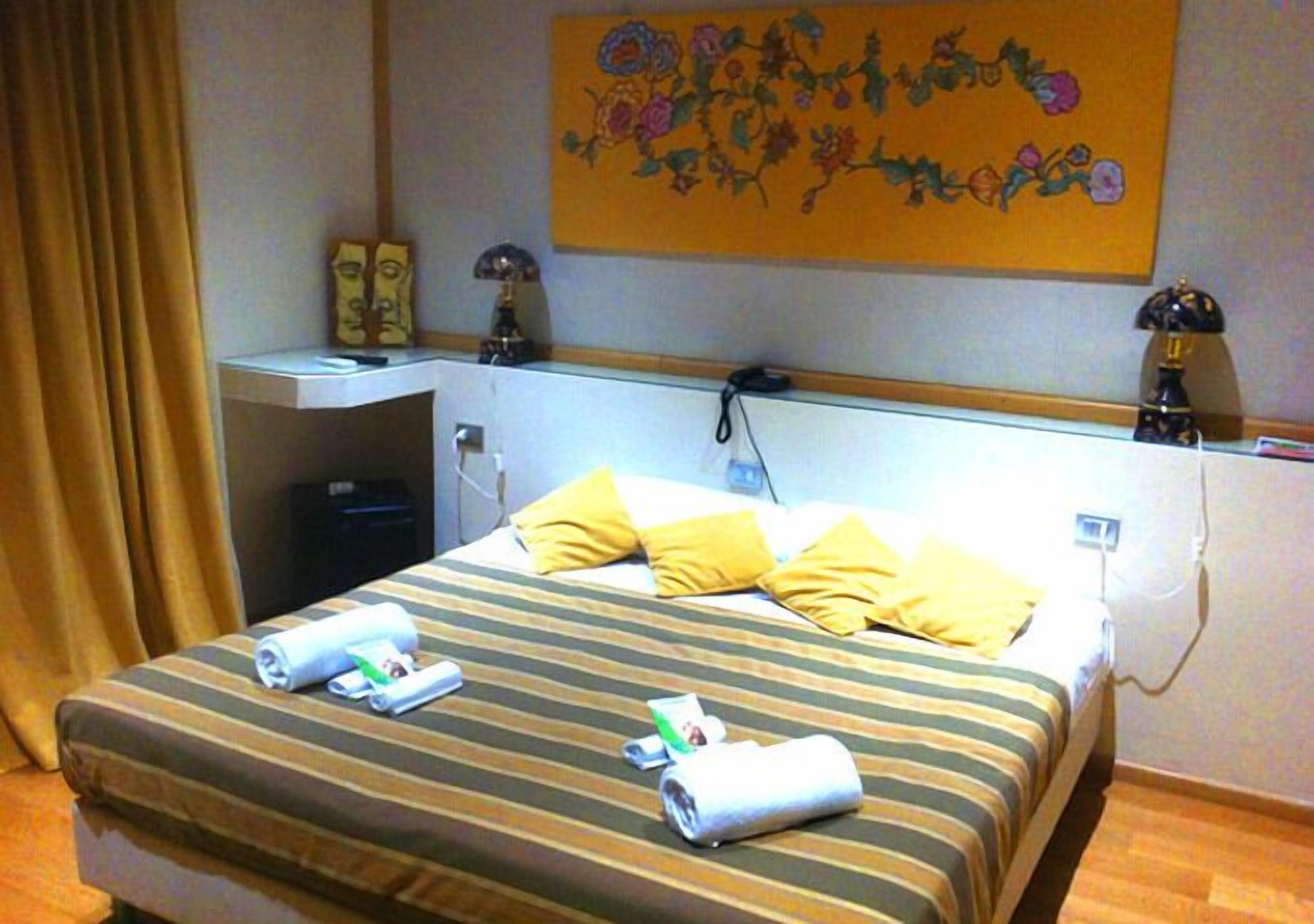 Ein Hotelzimmer mit einem Bett, einem Schreibtisch, einem Sessel, einer Lampe und einem Bild an der Wand.